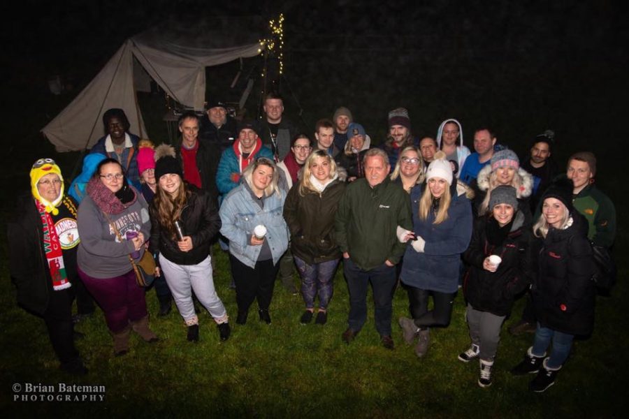 Group of people standing in dark with hot drinks.